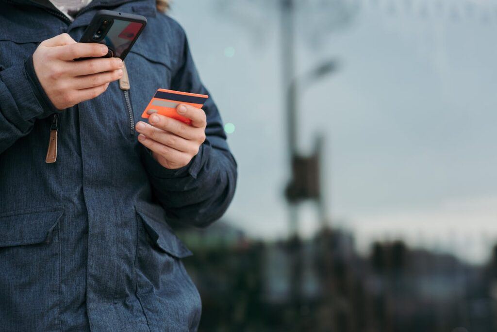 Male taking photo of credit card on smartphone on street in daytime